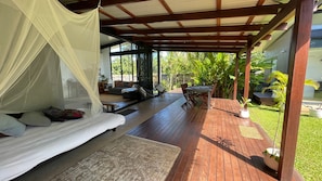 Un espacio al aire libre techado con una cama, asientos y una mesa.