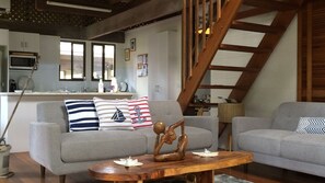 A living room with two grey sofas, a wooden coffee table, and a staircase. - Beach Villa 4- Beachfront views (Wongaling Beach)