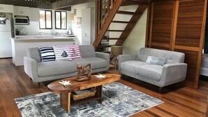 A living room with two grey sofas, a wooden coffee table, and a kitchen in the background. - Beach Villa 4- Beachfront views (Wongaling Beach)