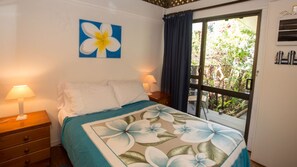 Et hotelværelse med en seng, to sengeborde med lamper, et vindue med gardiner og en væg med et blomsterbillede.