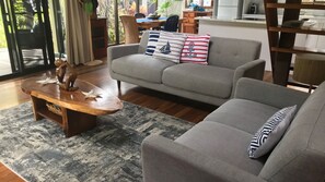 A living room with a grey sofa, a wooden coffee table, and a patterned rug. - Beach Villa 4- Beachfront views (Wongaling Beach)