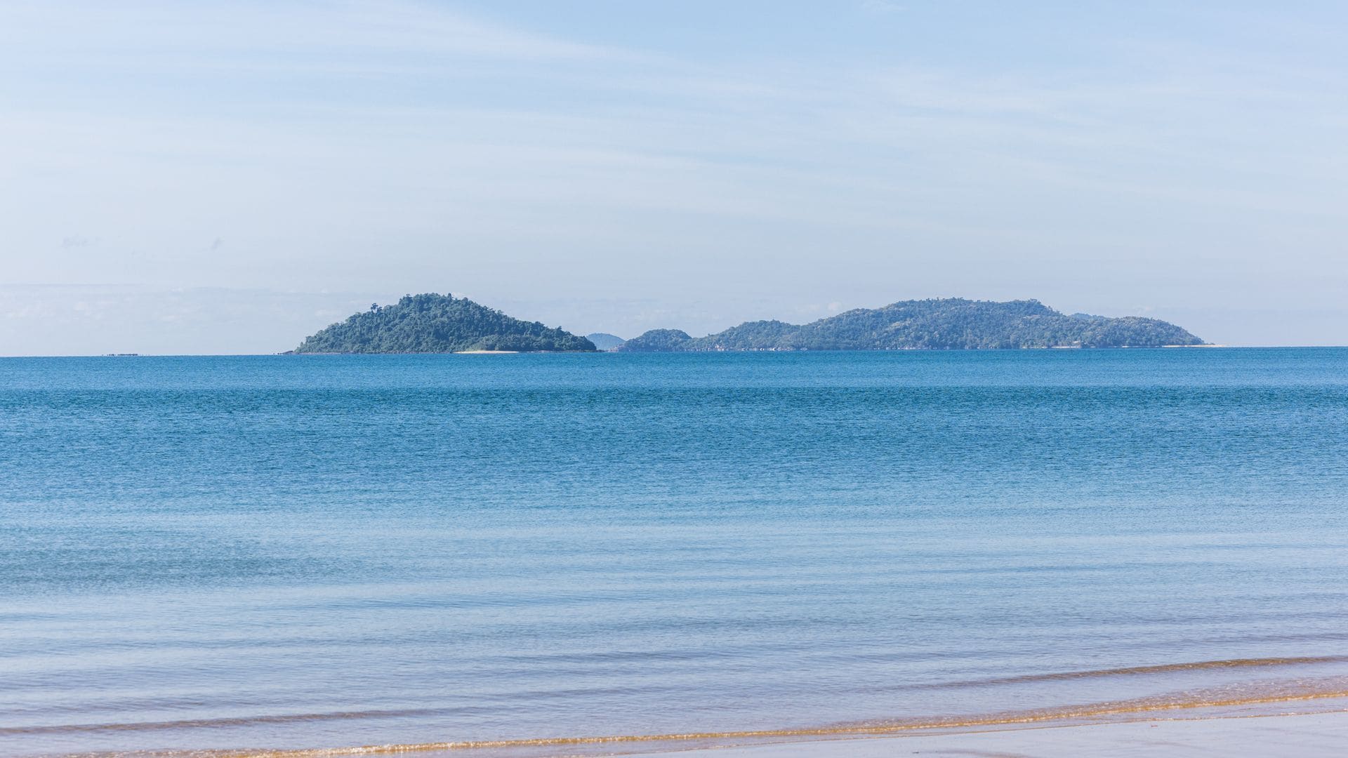 A calm sea with two small islands in the distance.