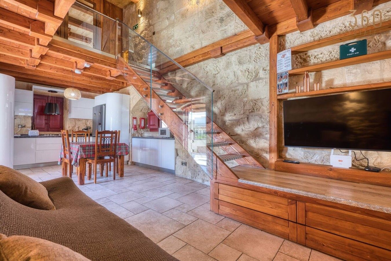 A spacious living area with a wooden staircase, a dining set, and a television.