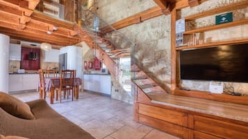 A spacious living area with a wooden staircase, a dining set, and a television.