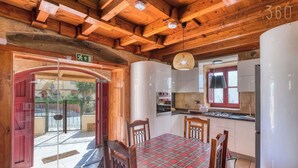 Un interno in legno con tavolo da pranzo, sedie, angolo cottura e una porta vetrata che dà sull'esterno.