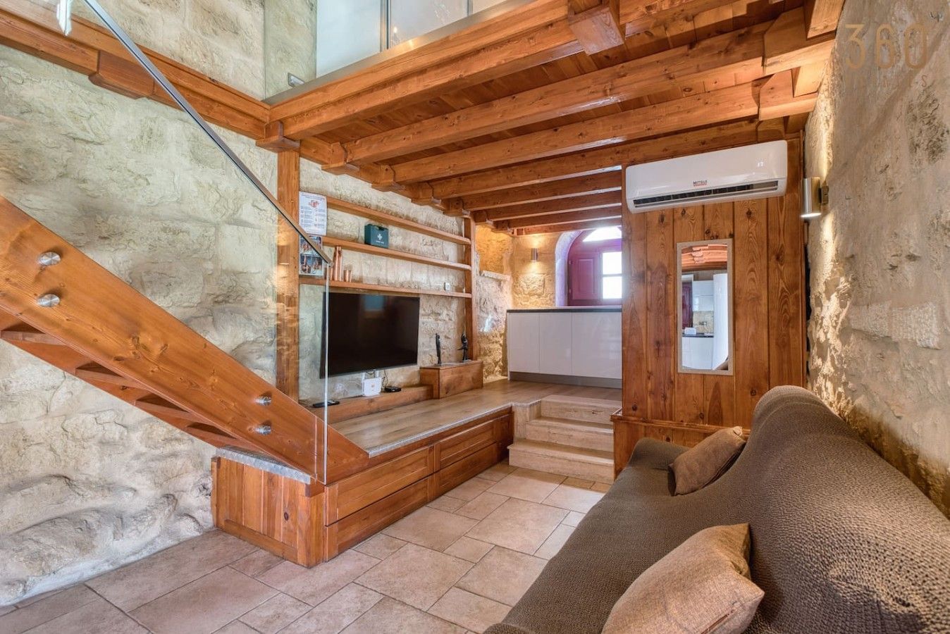 A wooden interior with a staircase, a flat-screen TV, and a sofa.