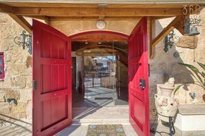 A red door leading to a building with stone walls and a wooden ceiling.