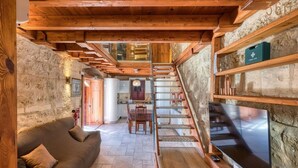 Un interno rustico con una scala in legno, un divano e una televisione.