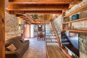 Ein rustikales Interieur mit einer Holztreppe, einem Sofa und einem Fernseher.