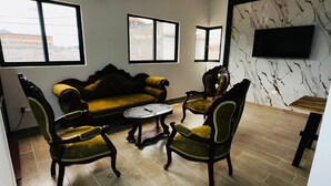 Un salon comprenant un canapé, deux fauteuils, une table basse et un téléviseur à écran plat fixé au mur.