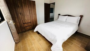 Une chambre à coucher avec un lit, une armoire en bois et une porte.