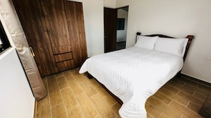 Ein Schlafzimmer mit einem Bett, einem Holzschrank und einer Tür.