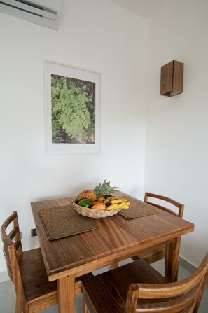 Une table à manger avec un set de table en fibres tressées, un panier de fruits et des chaises en bois.