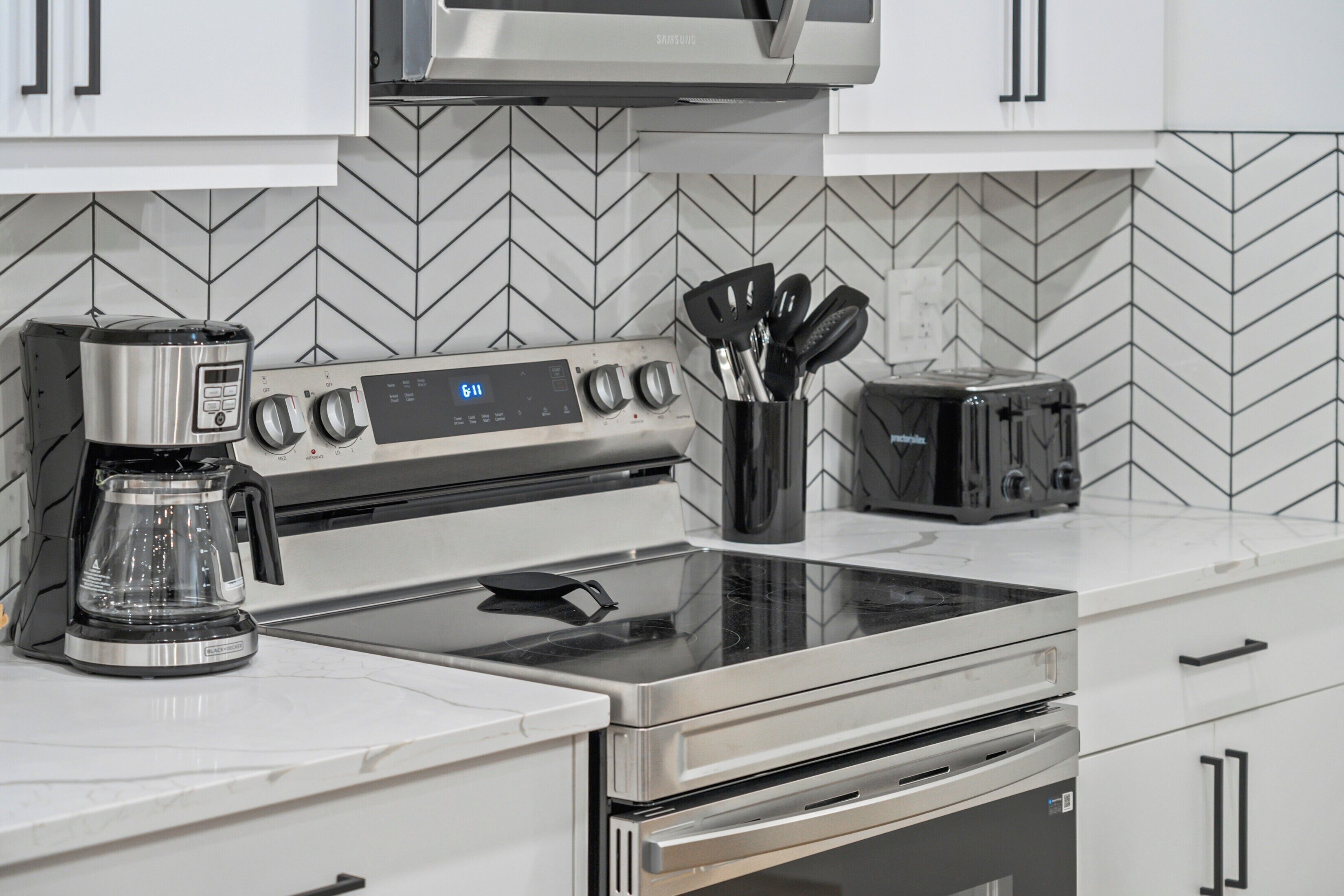 Una cocina equipada con microondas, cafetera, tostadora y un juego de utensilios.