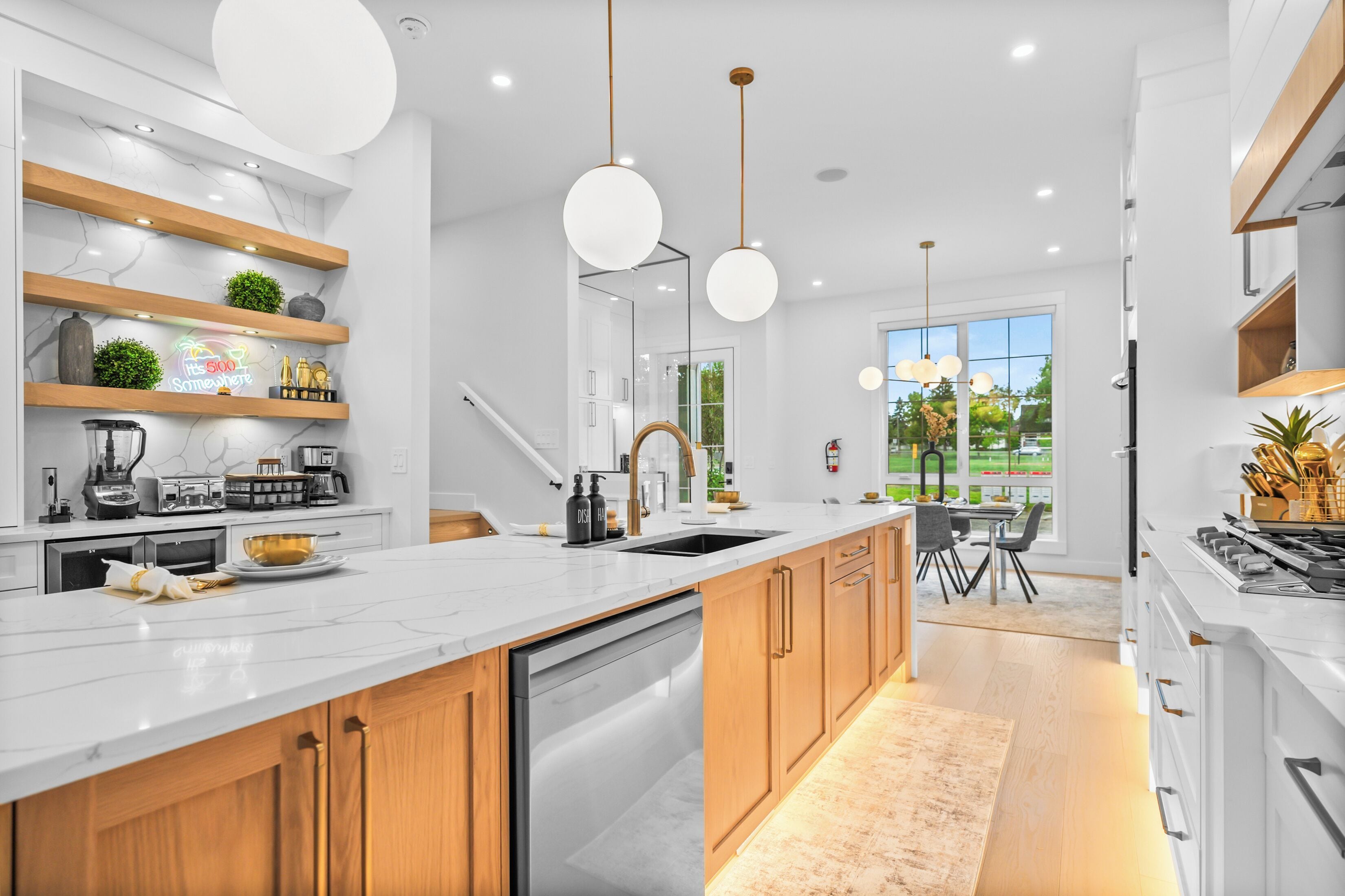 Une cuisine moderne dotée d’un îlot central, de meubles en bois et de luminaires suspendus.