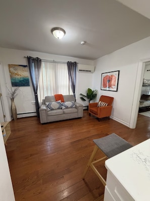 A living room with a sofa, armchair, and a dining area with a table.