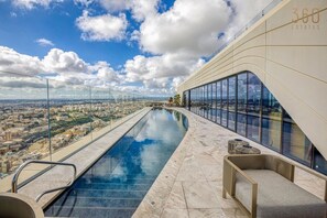 A rooftop infinity pool with a city view, a modern architectural design, and a clear sky. - 1BR 30th-Floor HIGH END Sea View in Mercury Tower (St. Julian`s)