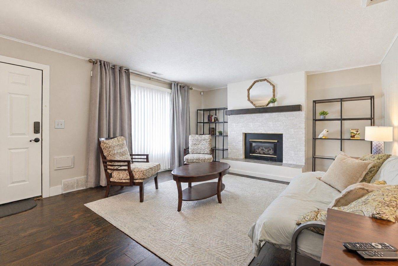 A living room with a fireplace, a sofa, a coffee table, and two patterned chairs.