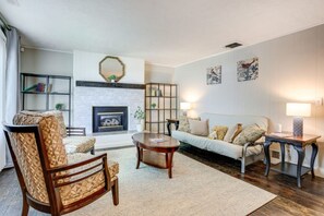 A living room with a fireplace, a sofa, a coffee table, and a bookshelf. - Ogden Apt Near Downtown w Yard and Fire Pit (Ogden)