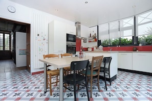 Una cocina moderna con comedor, que incluye una isla grande, electrodomésticos integrados y vistas a través del ventanal.