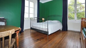 Quarto com uma cama de solteiro, uma mesa de madeira e uma cadeira.