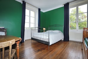 Una habitación con una cama individual, una mesa de madera y una silla.