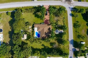 En boligejendom med swimmingpool, omgivet af frodig vegetation og palmer.