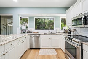 A modern kitchen with white cabinets, a stainless steel dishwasher, a built-in oven, and a microwave. - Private Pool Paradise in Sea Pines Resort 3BR 3B (Hilton Head Island)