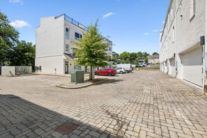 A paved courtyard with a tree, a red car, and a white van parked. - Furnished Monthly- 3BR Rooftop- East Nashville (Nashville)