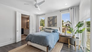 A bedroom with a bed, bedside table, lamp, and a large window with a view. - Furnished Monthly- 3BR Rooftop- East Nashville (Nashville)