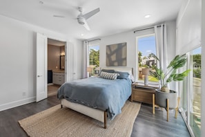 A bedroom with a bed, bedside table, lamp, and a large window with a view. - Furnished Monthly- 3BR Rooftop- East Nashville (Nashville)