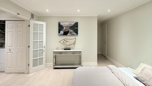Quarto com cama, penteadeira, espelho e um quadro na parede.