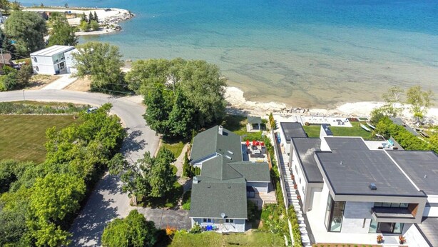 Uma área residencial à beira-mar, com casas, vista desimpedida do oceano e uma estrada que leva à praia.