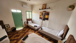 Een kamer met twee eenpersoonsbedden, een groene deur, een schilderij aan de muur en een vloer met een patroon.