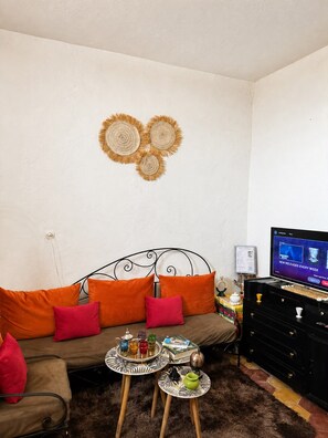 A living room with a sofa, a television, a decorative wall piece, and a small table with items. - 3-bedroom apartment with a private terrace, 5 minutes from Jemaa el-Fna (Marrakech)