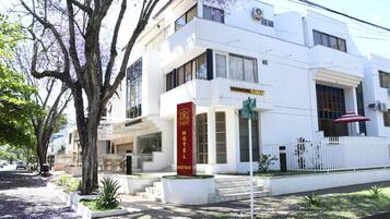 Um edifício branco com uma placa vermelha indicando um hotel e boutique.