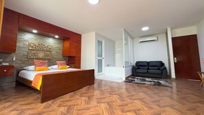 Ein Schlafzimmer mit einem hölzernen Bett, einer Couch und einem Badezimmer mit Glastür.