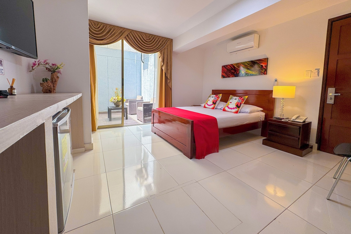 Une chambre d’hôtel équipée d’un lit, d’un bureau, d’une chaise, d’une télévision, d’une fenêtre avec des rideaux et d’un appareil de climatisation.