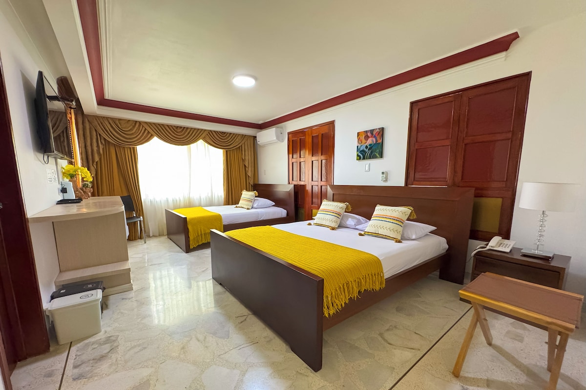 Une chambre d’hôtel avec deux lits, un bureau, une chaise, une télévision et un téléphone.
