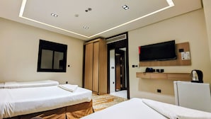 Habitación de hotel con dos camas, televisión, minibar y puerta que da a un baño.