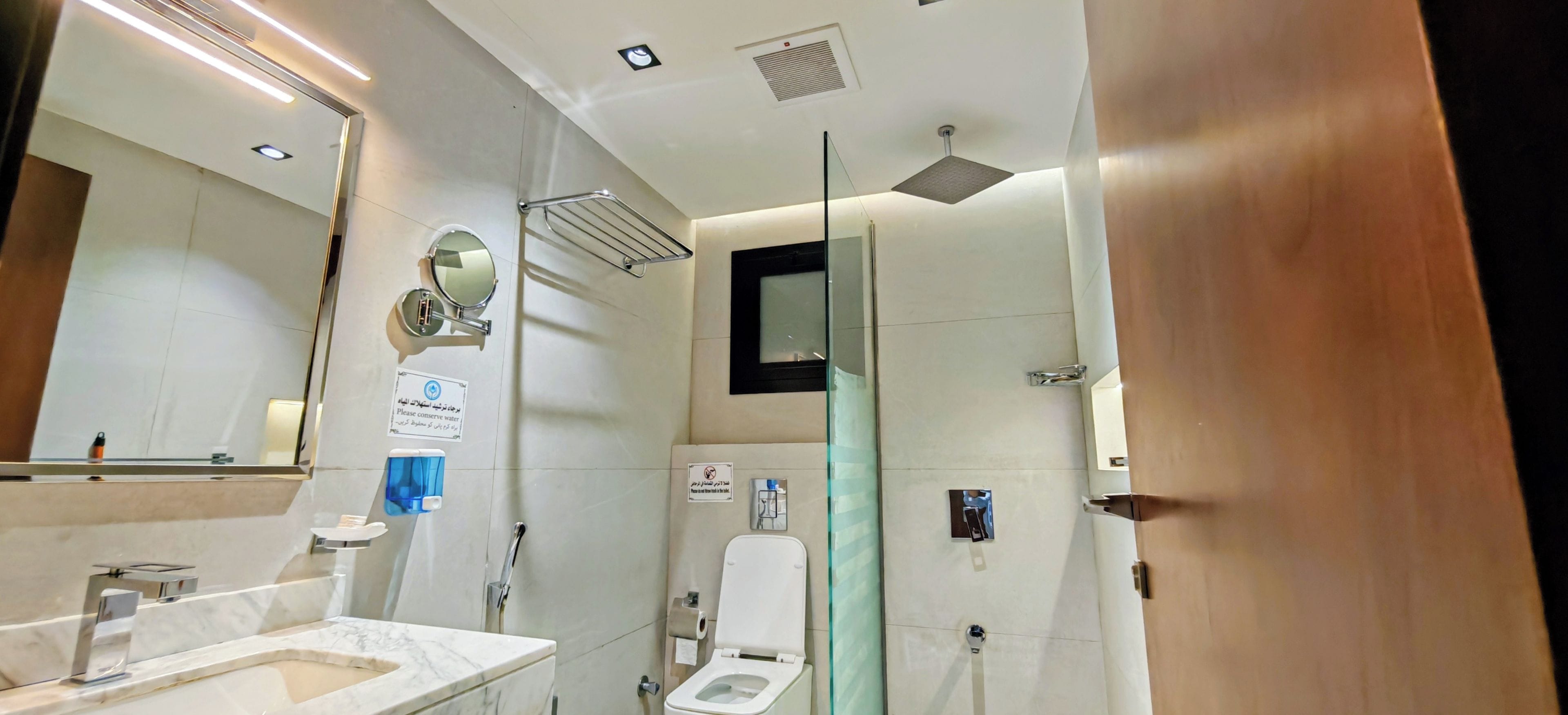 A modern bathroom with a marble sink, a toilet, and a glass partition.