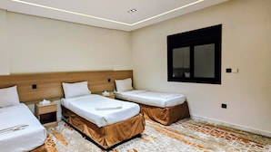 Quarto de hotel com duas camas, uma mesinha de cabeceira, um espelho e piso estampado.