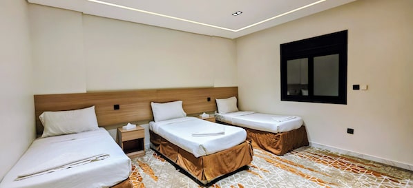 A hotel room with two beds, a nightstand, a mirror, and a patterned floor.