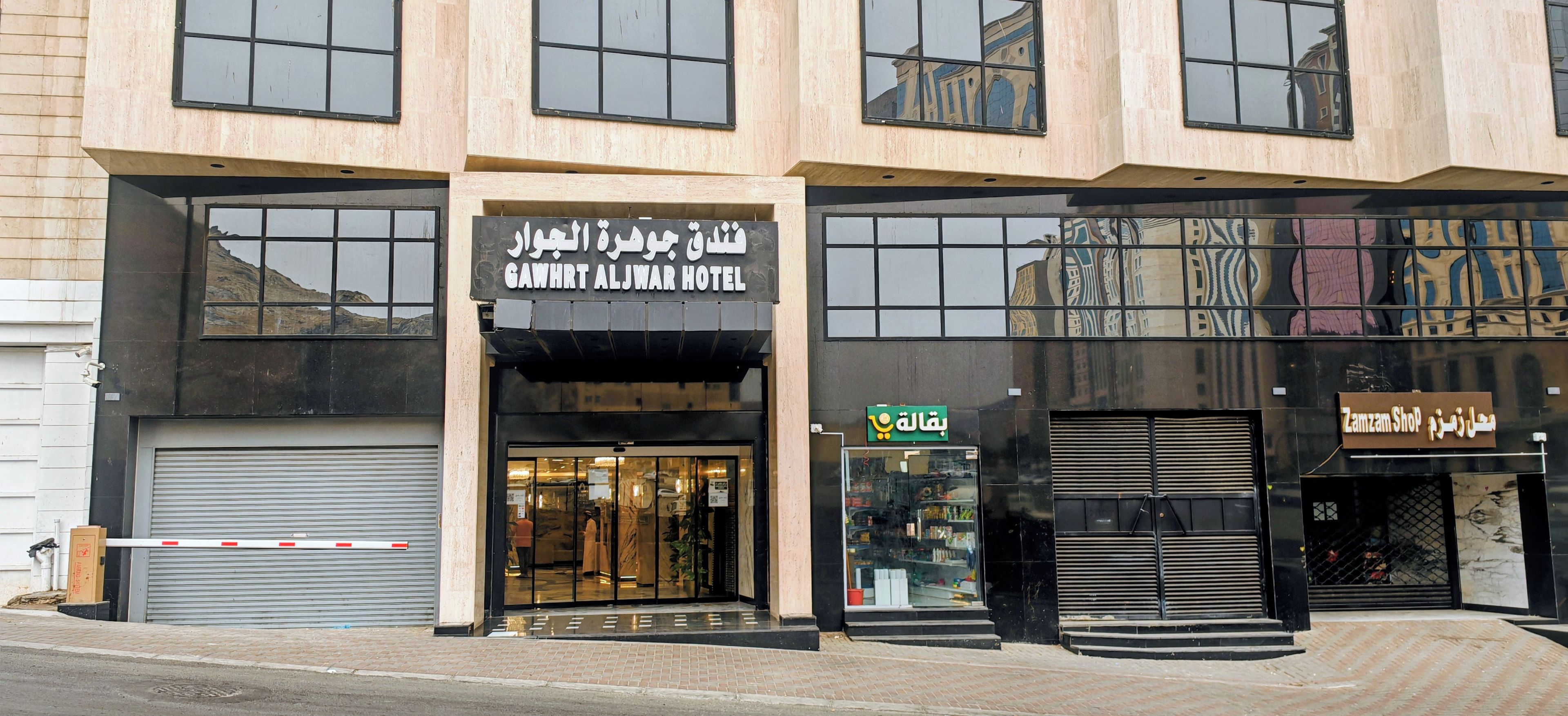 Un hôtel à la façade moderne, doté de grandes fenêtres et d’une devanture avec une enseigne indiquant la présence d’un commerce.
