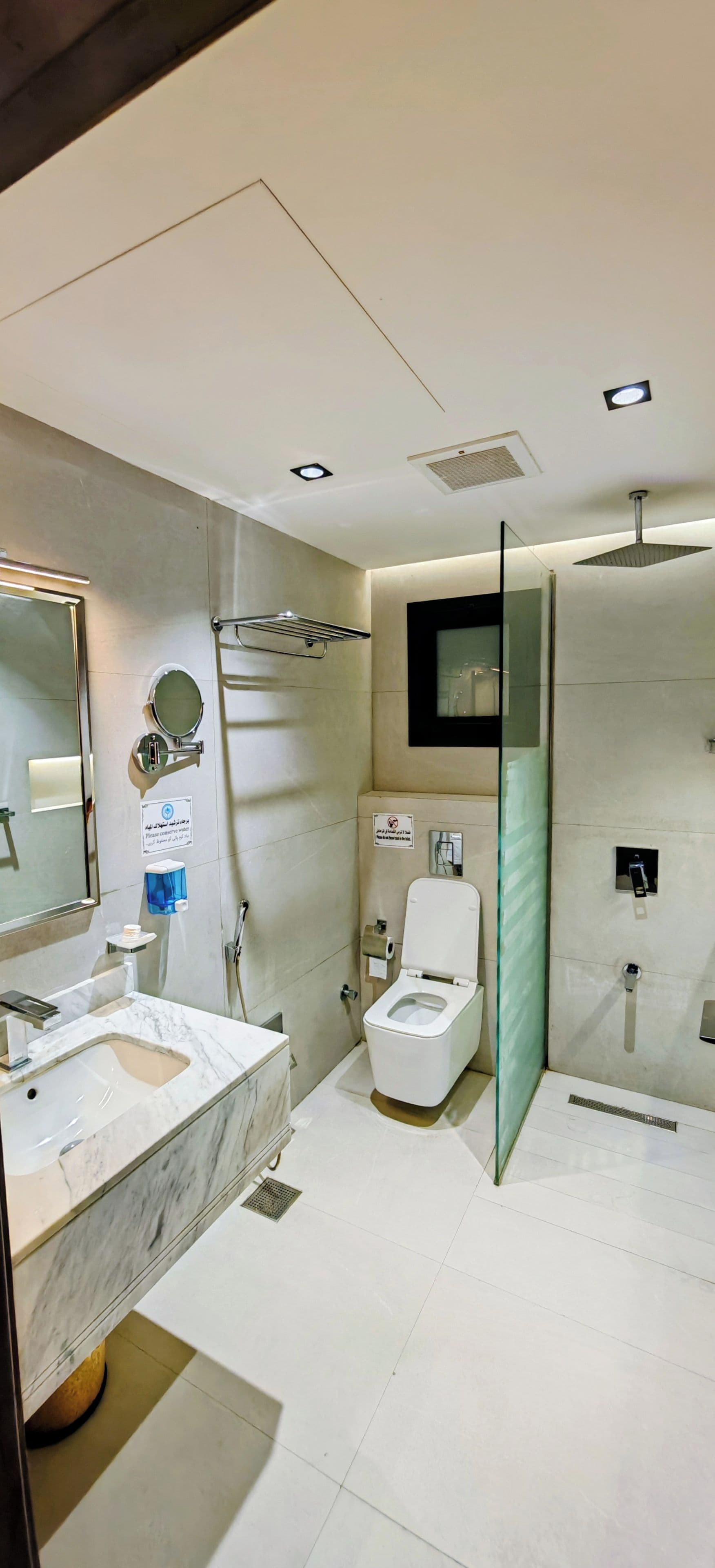 A modern bathroom with a marble sink, a toilet, and a glass shower enclosure.