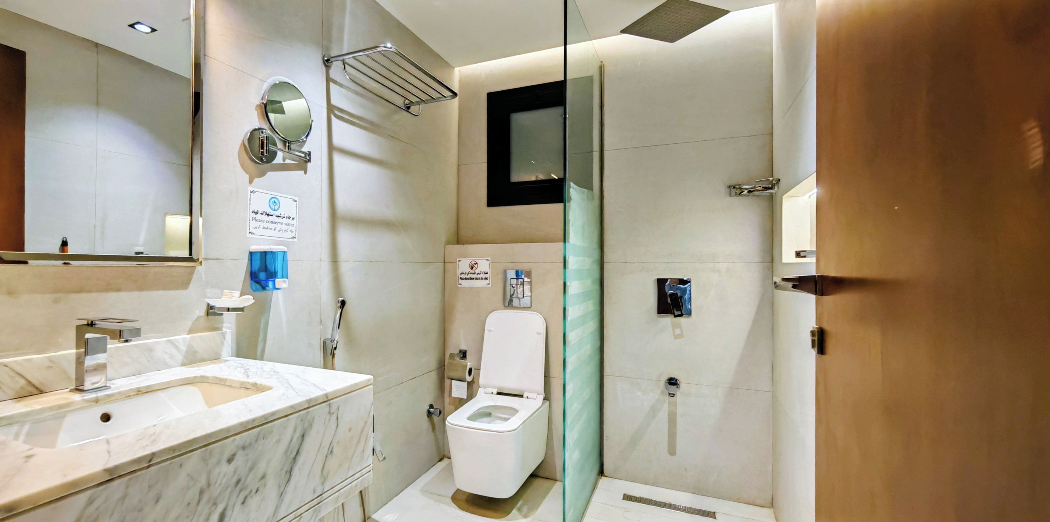 Un baño moderno con lavabo de mármol, inodoro y zona de ducha.