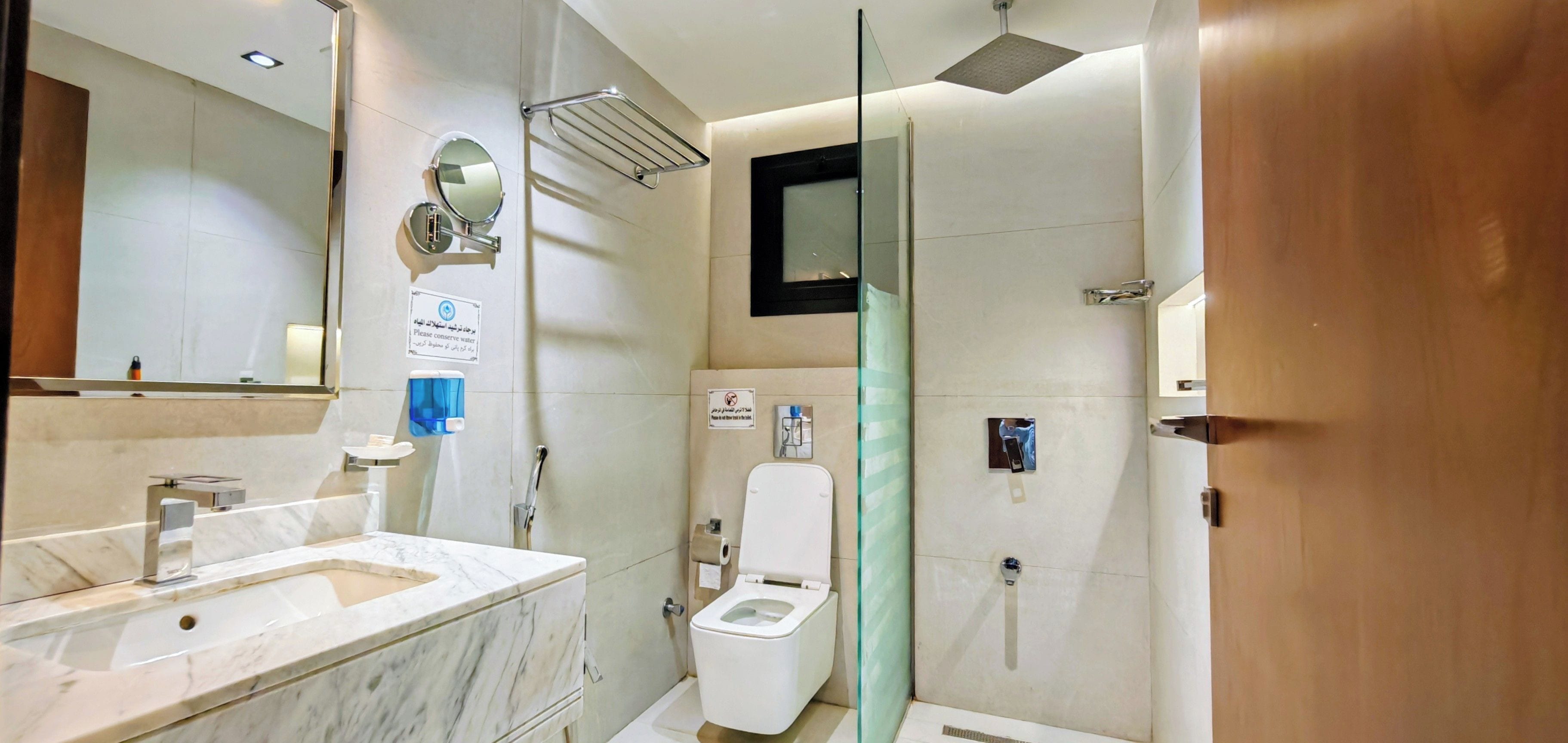 Ein modernes Badezimmer mit Marmorwaschbecken, Toilette und Duschbereich.