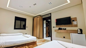Habitación de hotel con dos camas, televisión, minibar y puerta de baño.
