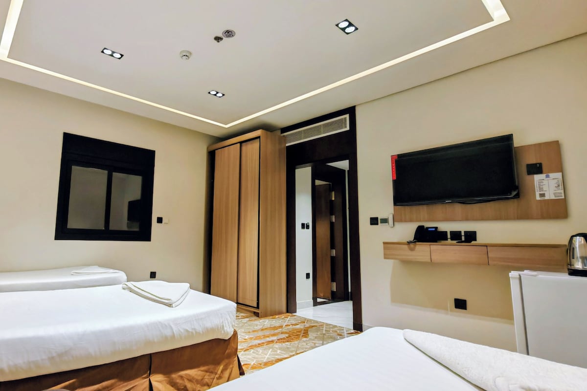 Ein Hotelzimmer mit zwei Betten, einem Fernseher, einer Minibar und einer Badezimmertür.