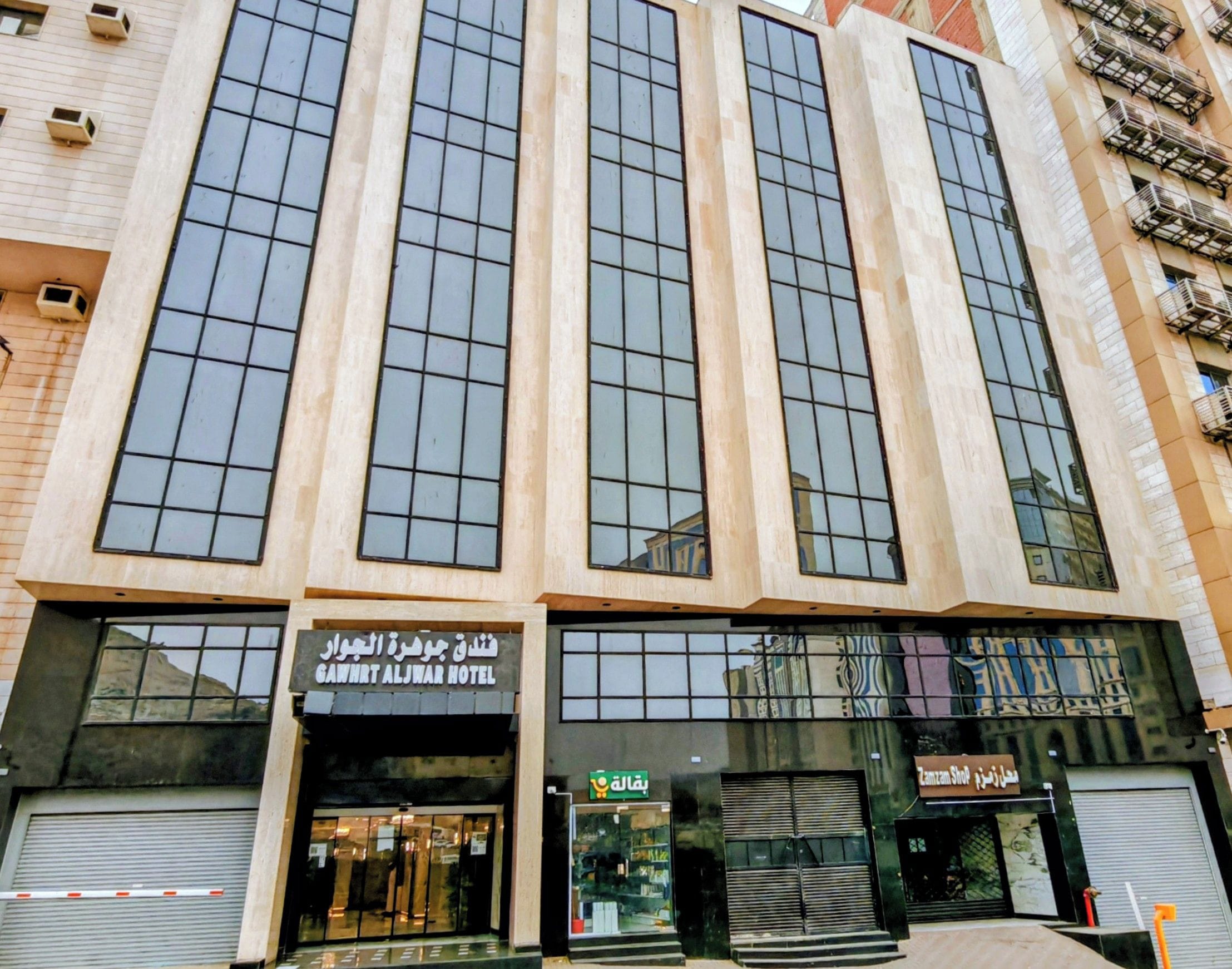 A hotel with multiple floors, large windows, and a storefront with a sign.